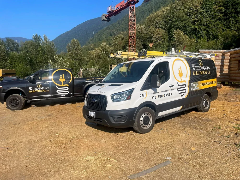 The Wire Guys van and pickup truck parked on a log-home build site in the Harrison and Agassiz area