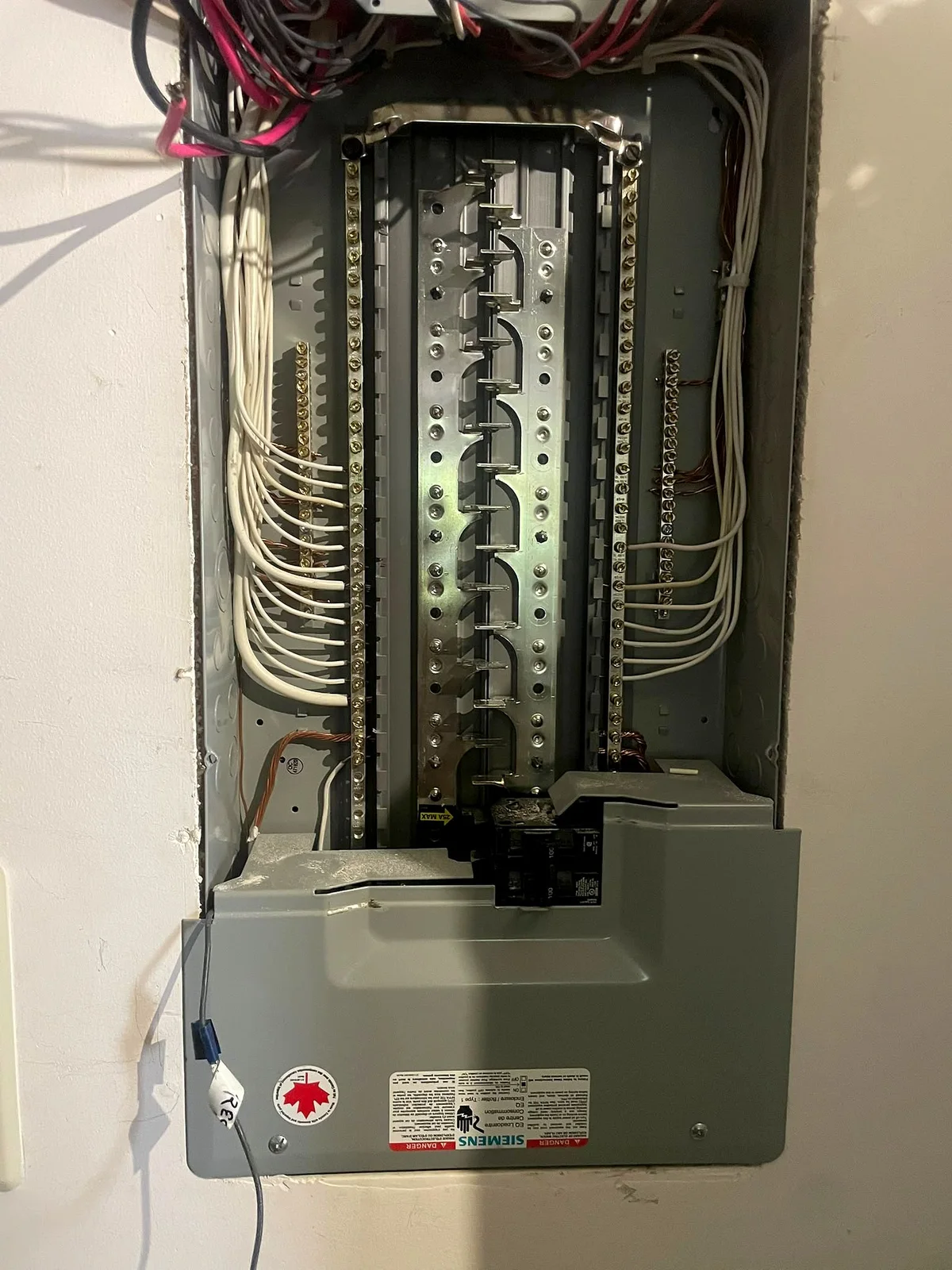 Electrical panel enclosure with the bus bars exposed and neutral wires landed down both sides